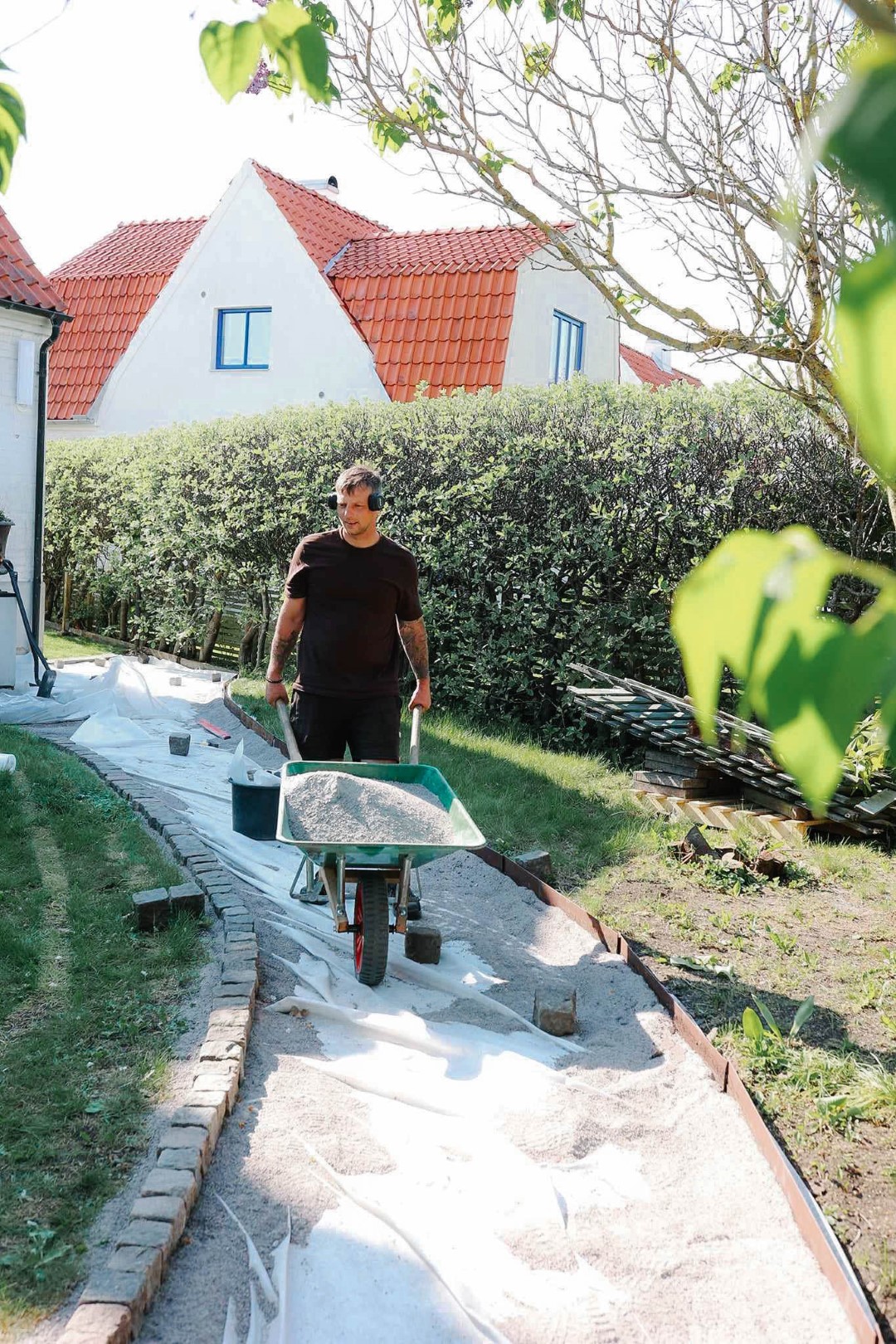 Trädgårdsarbetare kör skottkärra med sand vid anläggningsarbete